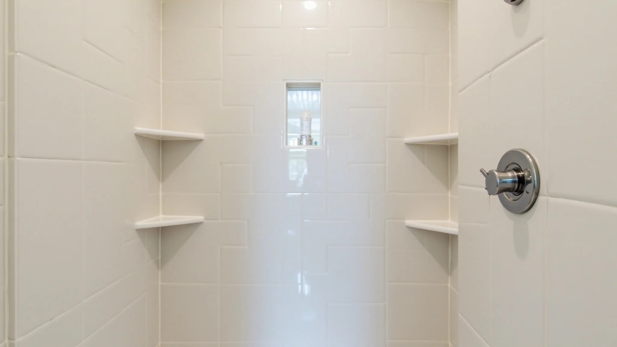 Banheiro com nichos embutidos dentro do box, com shampoo e sabonete.