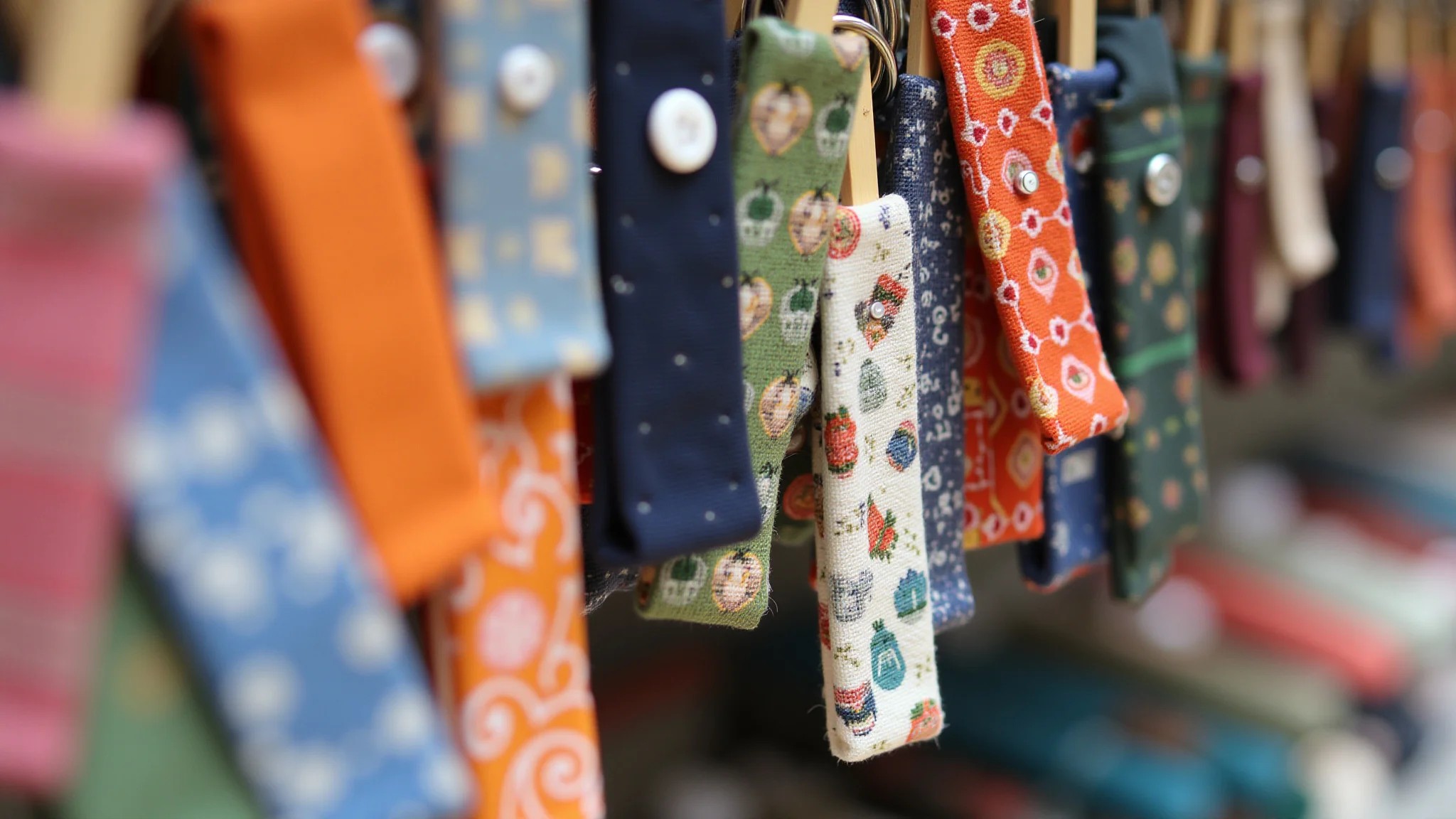 Close-up de chaveiros de tecido com estampas diversas e botões.