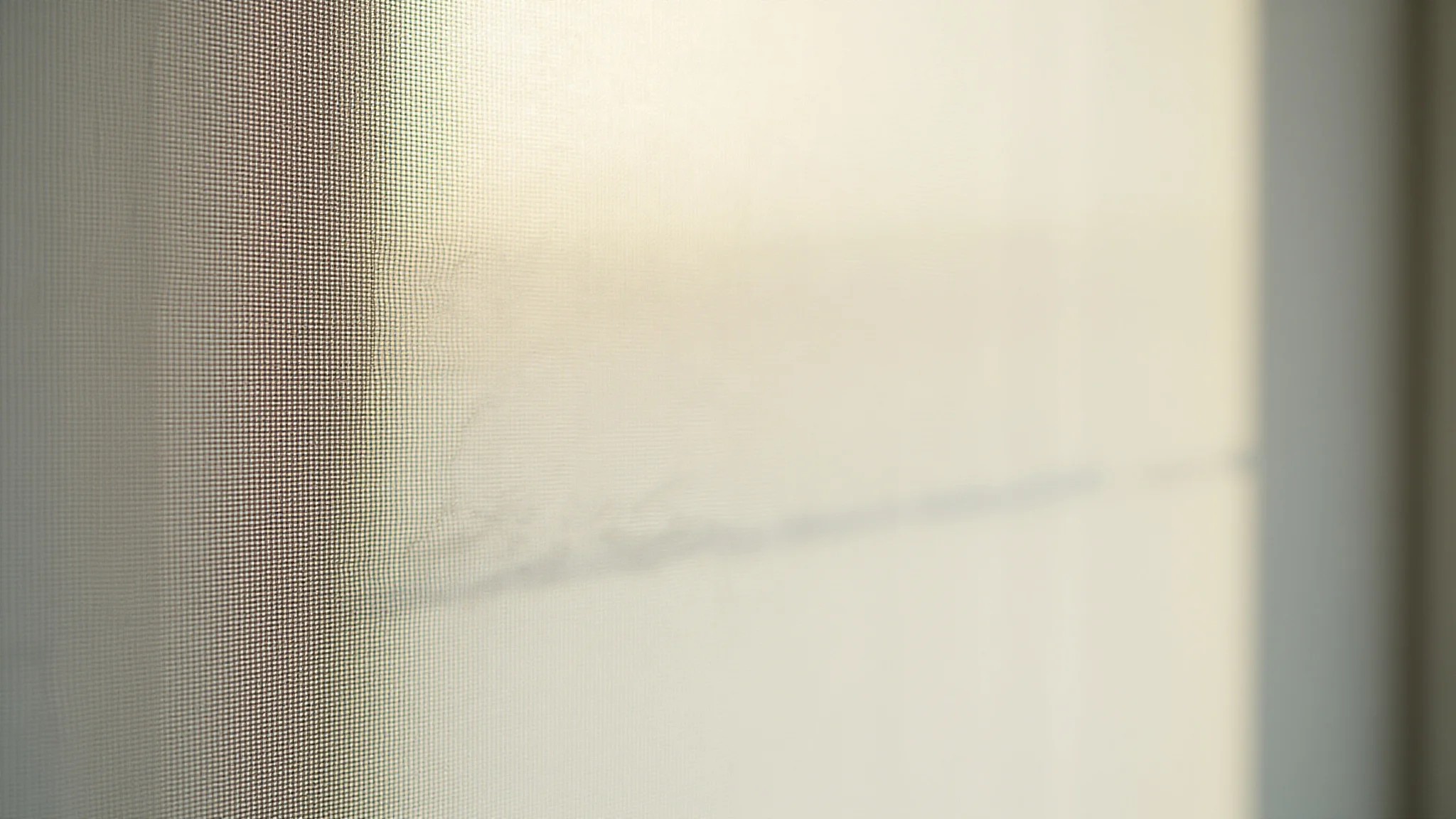 Detalhe da textura de cortina rolô screen com luz solar filtrada.