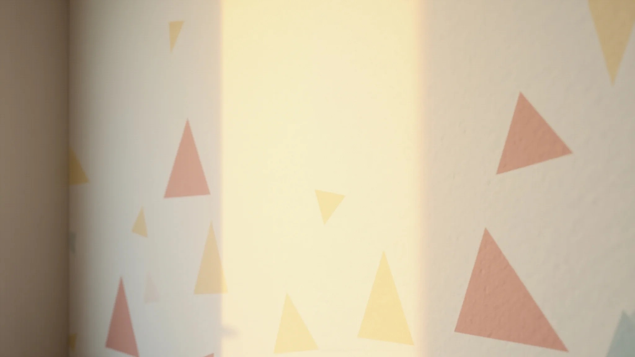 Detalhe de papel de parede geométrico com triângulos em tons pastel em quarto minimalista.