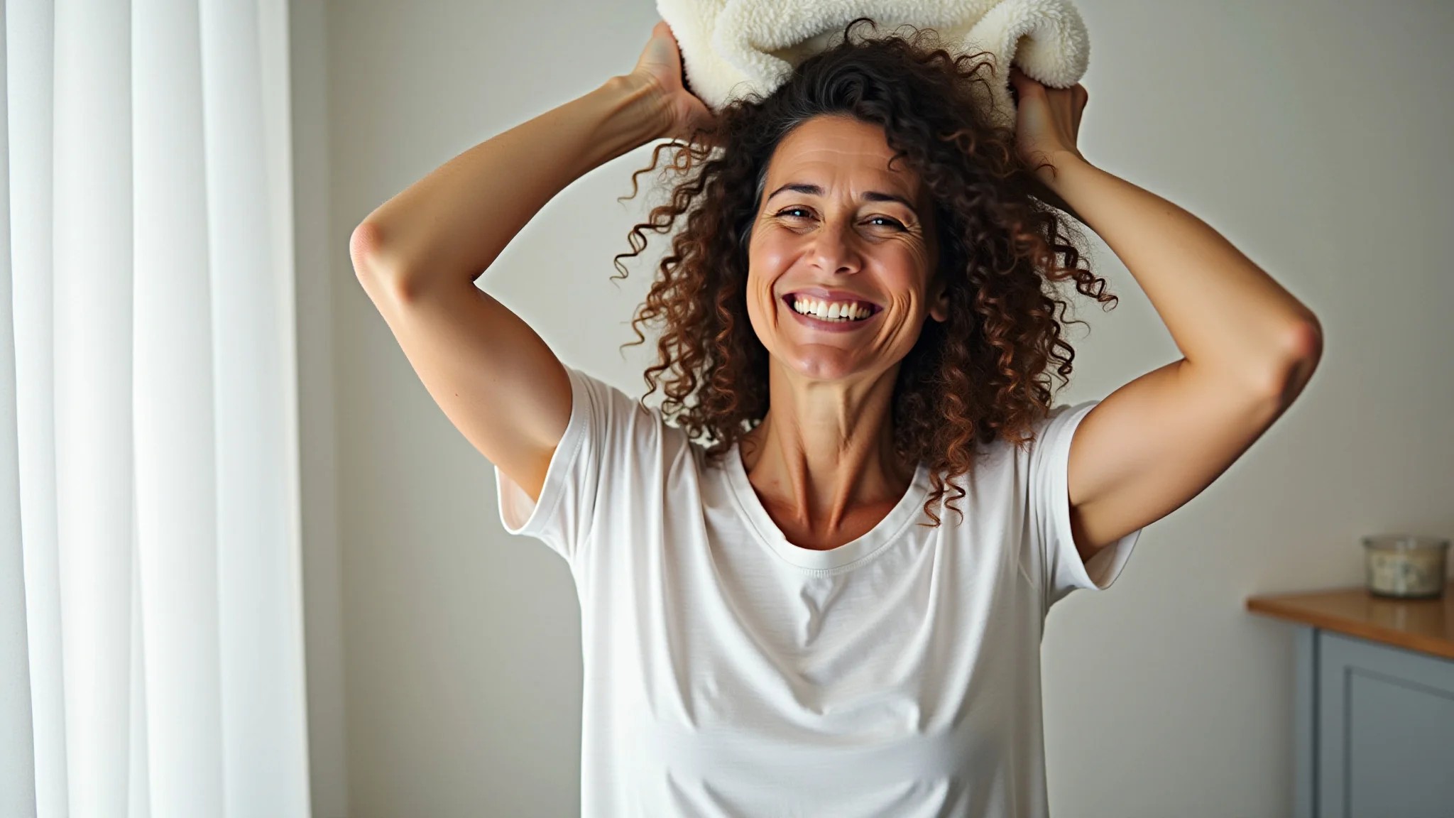 Mulher brasileira secando o cabelo cacheado com uma camiseta de algodão.