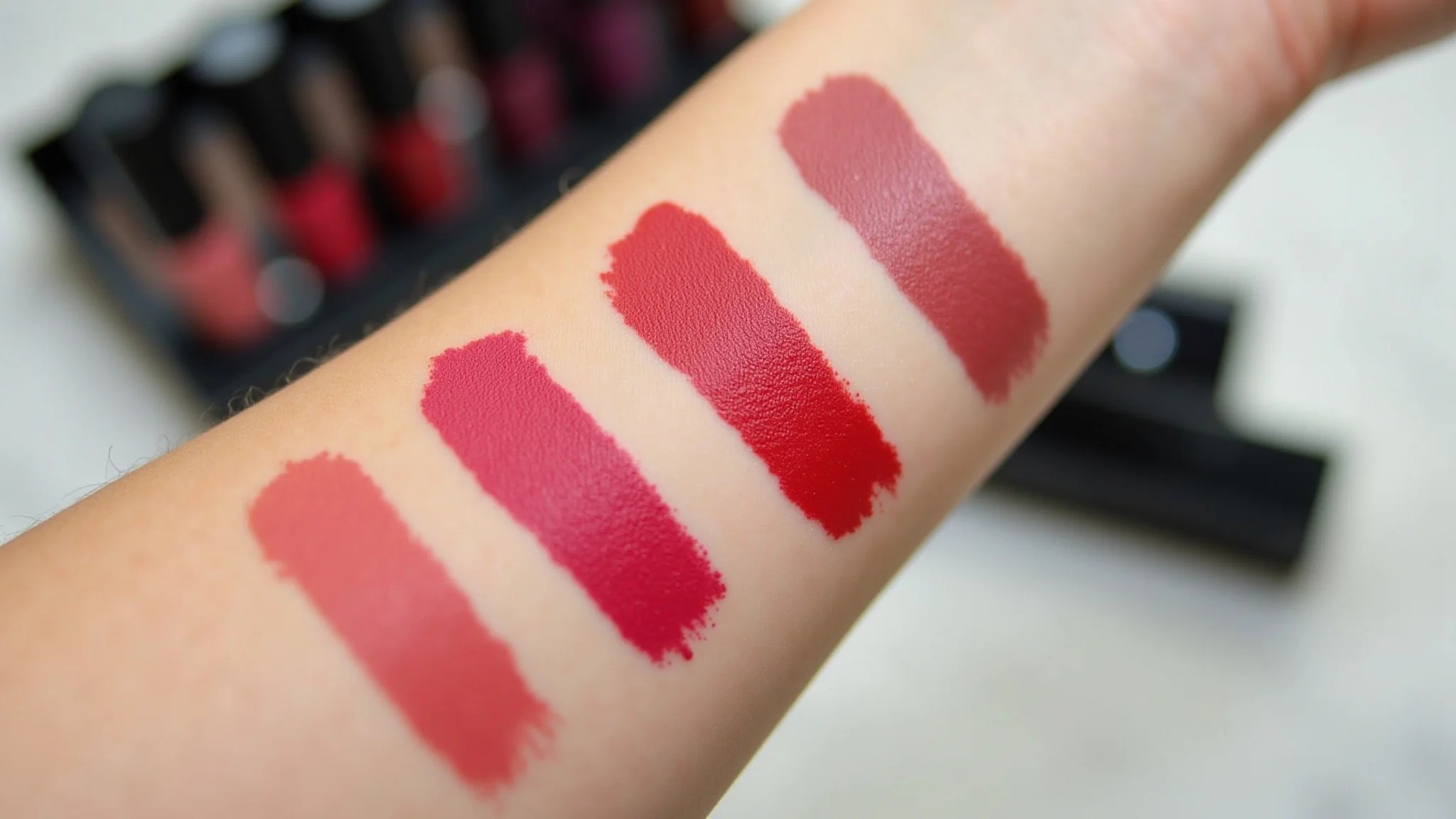 Amostras de batom matte em um braço, mostrando texturas e cores vibrantes.