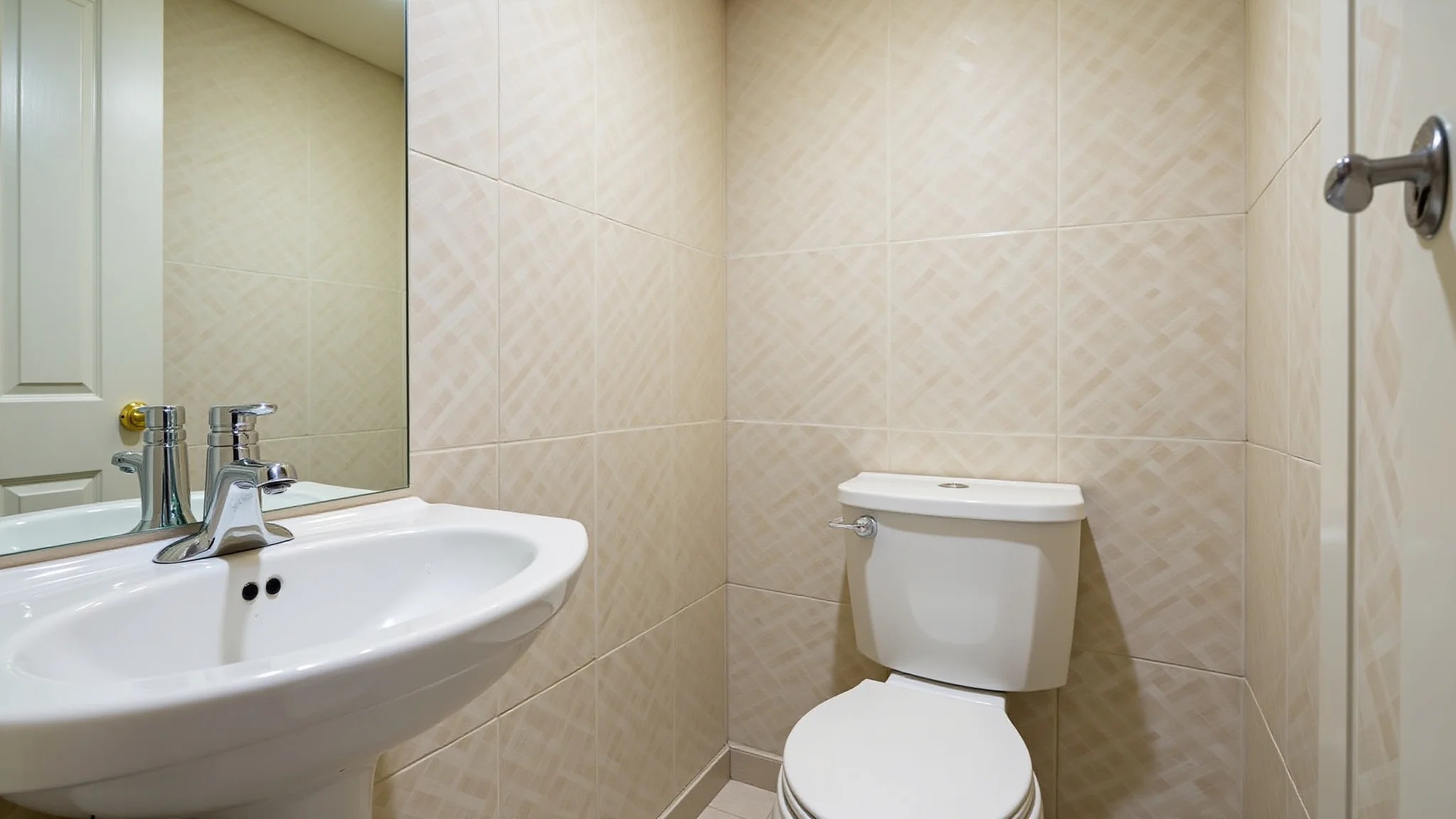 Lavabo pequeno e elegante com revestimento cerâmico claro e espelho ampliando o espaço.