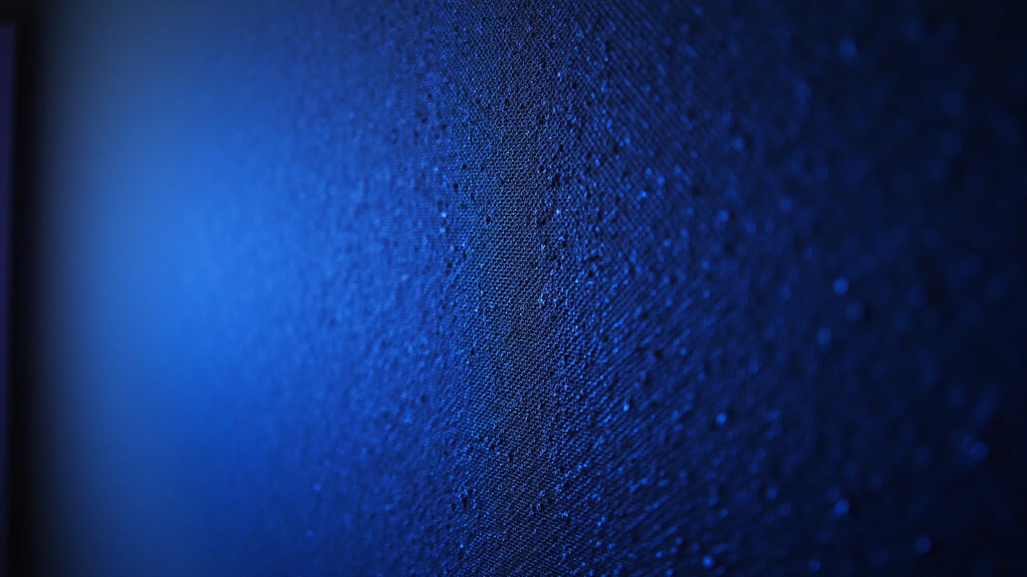 Parede de destaque em quarto gamer com papel de parede texturizado e azul neon.