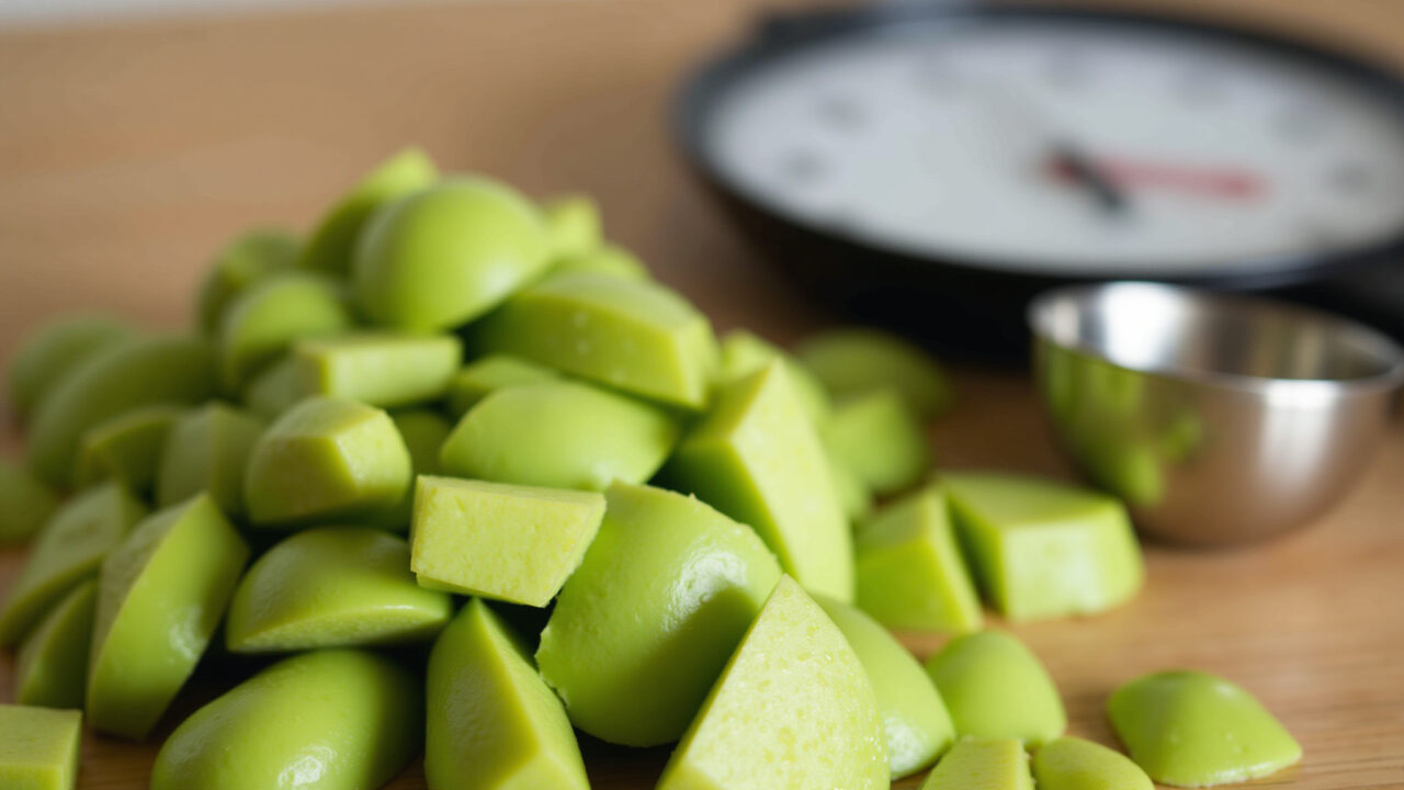 Close-up of chopped green papaya leaves, measuring spoon, kitchen scale, natural light, 8K, sharp Folhas de mamão verde picadas prontas para o chá.