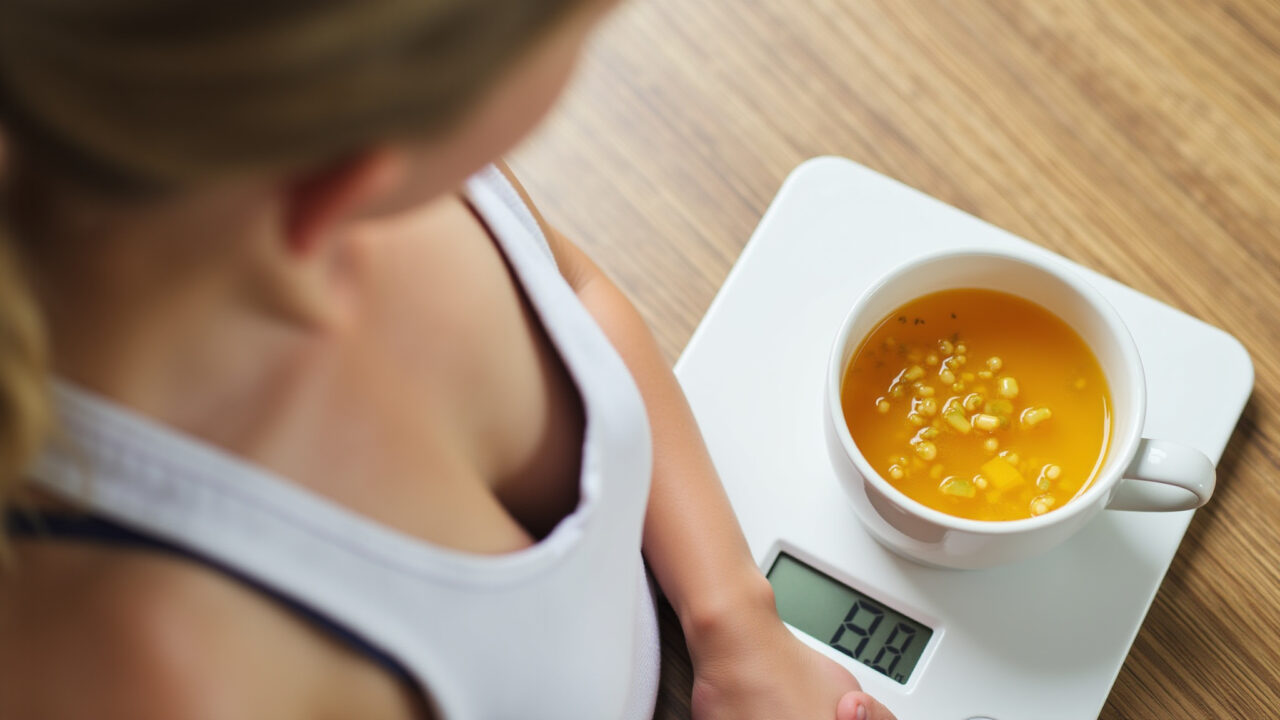 Woman on a scale next to a cup of mango leaf tea, healthy eating, natural light, 8k, lifestyle Chá de folha de manga e emagrecimento.