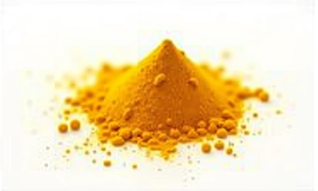 Pó de cúrcuma espalhado sobre fundo branco, com cor dourada vibrante.